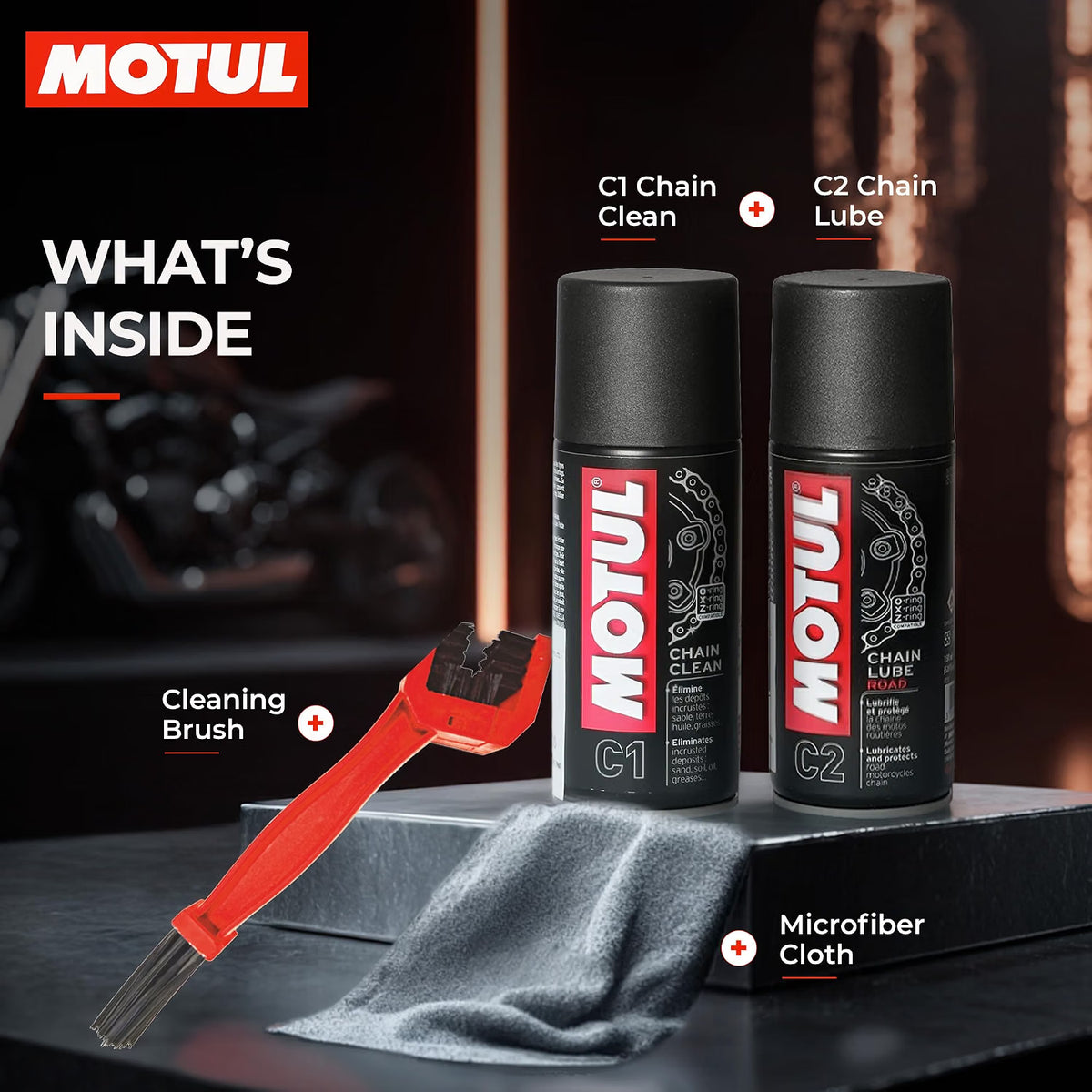 MOTUL Chain Clean C1 and C2 Chain Lube cans displayed on a dark surface with a red cleaning brush, gray microfiber cloth.
